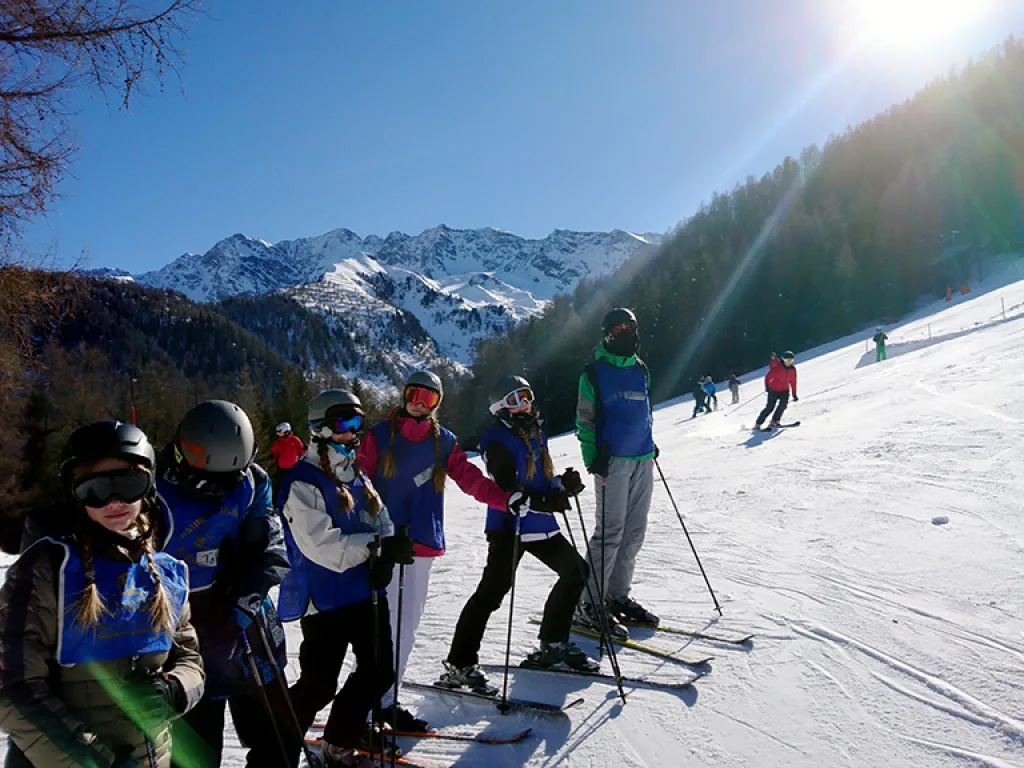Skigruppe steht im Gegenlicht am Pistenrand.
